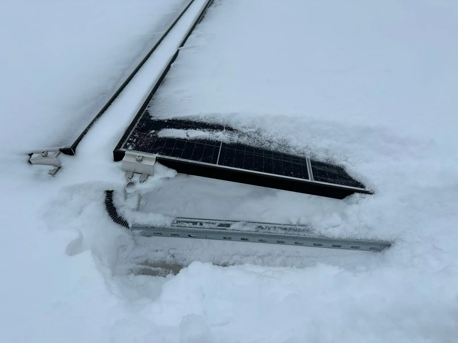 Snow-covered solar panels on a flat roof — the seasonal load Sense systems monitor