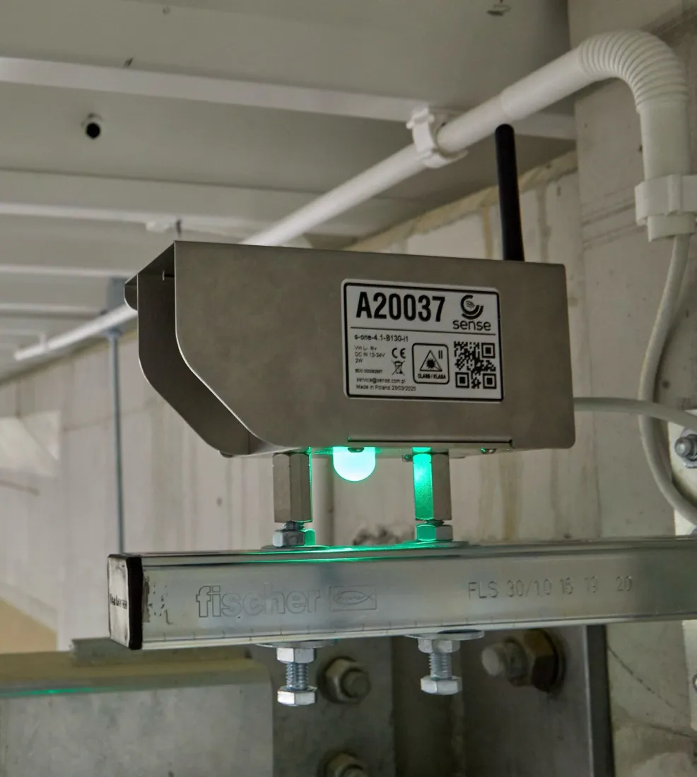 Sense S-One deflection sensor mounted on a roof support beam, with a green status indicator